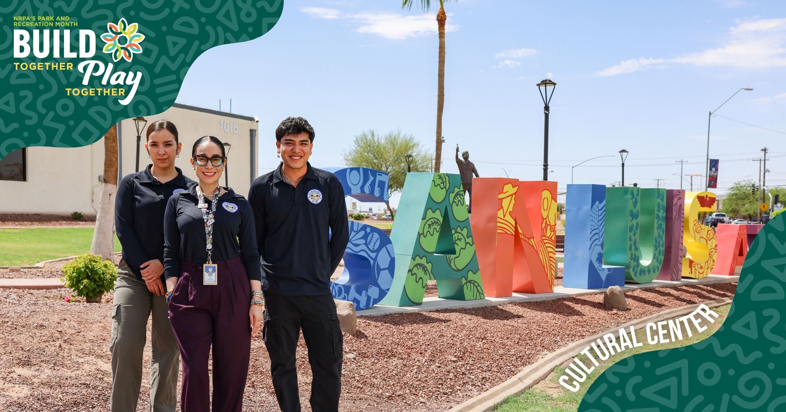 Three people stand in front of the Build Play Center sign, smiling and posing for the photo.