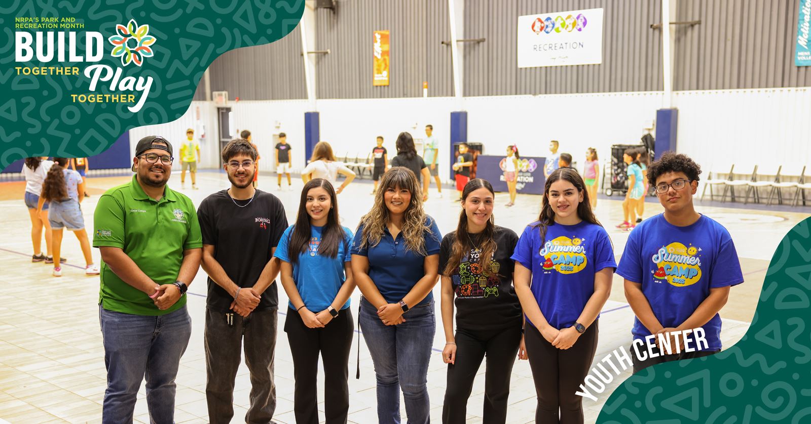 A diverse group of people stands in front of a banner that reads Build Play, smiling and engaging with each other.