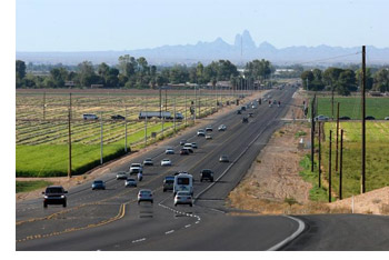 A busy highway with multiple cars traveling in both directions under a clear blue sky.